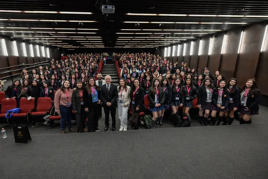 Large group of students and staff posing for a group photo in a lecture hall, many wearing lanyards.