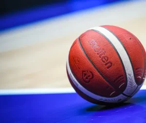 Close-up of an orange basketball on a blue indoor court with white lines.